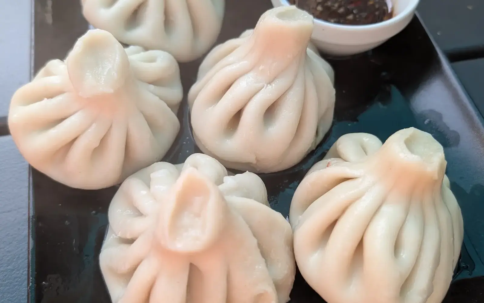 Chinkali mit Smetana und dunkler Soße auf einer schwarzen Platte
