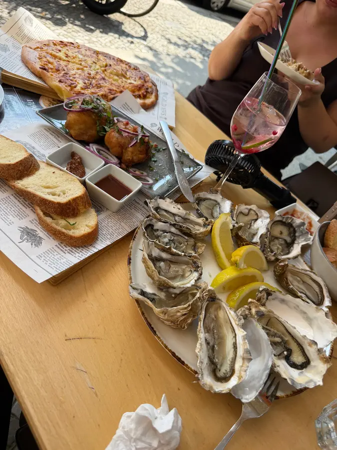 Austern mit Zitrone, Brot und ein Cocktail auf einem Holztisch