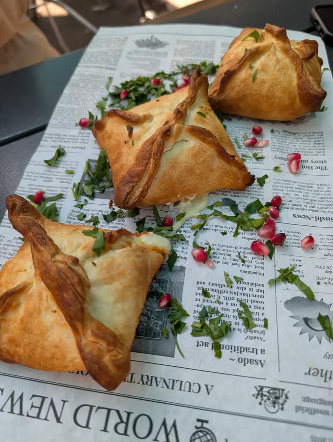 Gefüllte Teigtaschen mit Granatapfelkernen und Kräutern auf Zeitungspapier