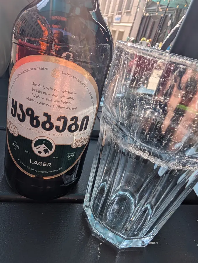 Flasche georgisches Lagerbier mit georgischer Schrift und ein Glas Wasser