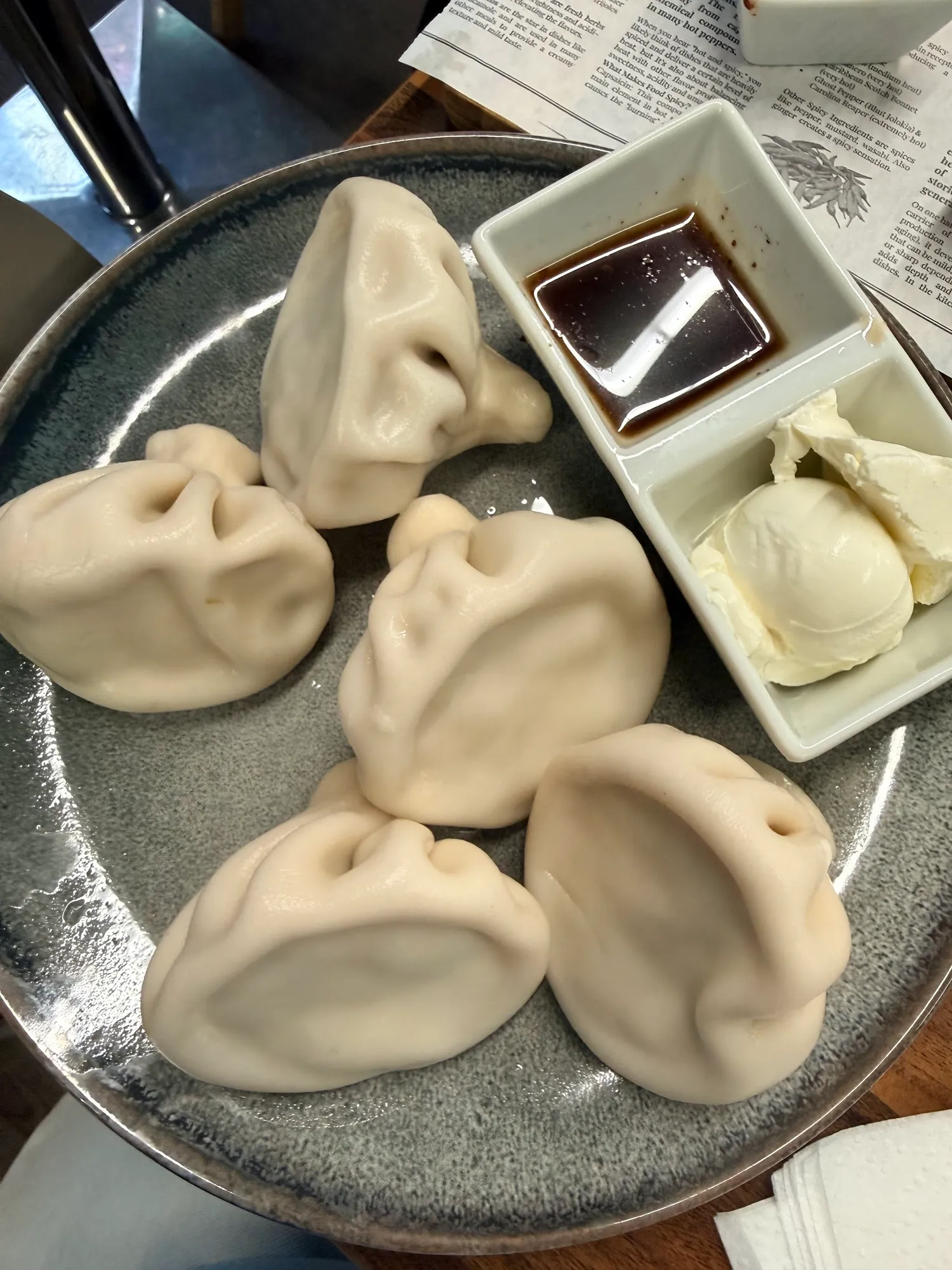 Chinkali auf einem grauen Teller mit Soße und Smetana